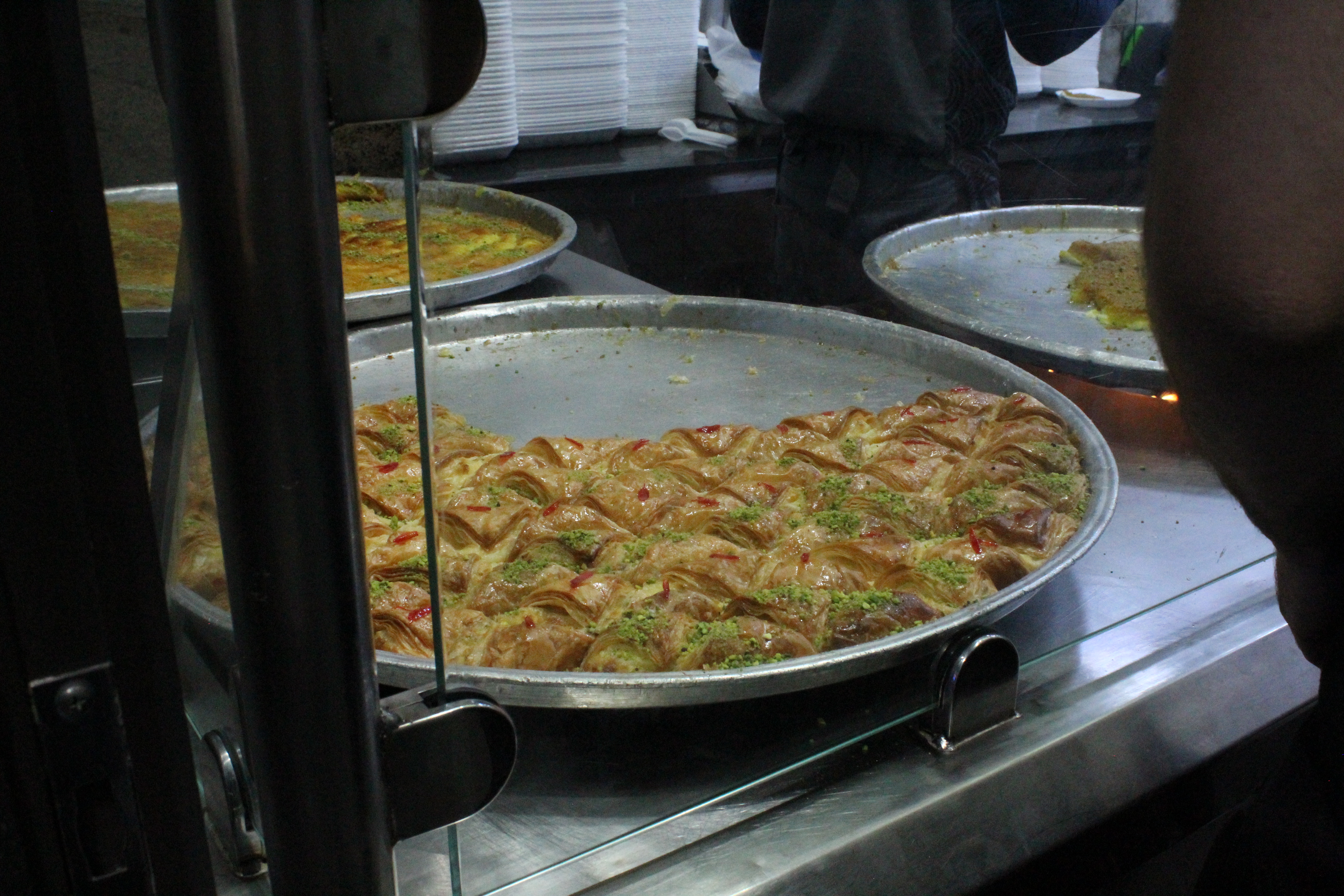 Large trays of baklava and pastries on display in a downtown Amman bakery