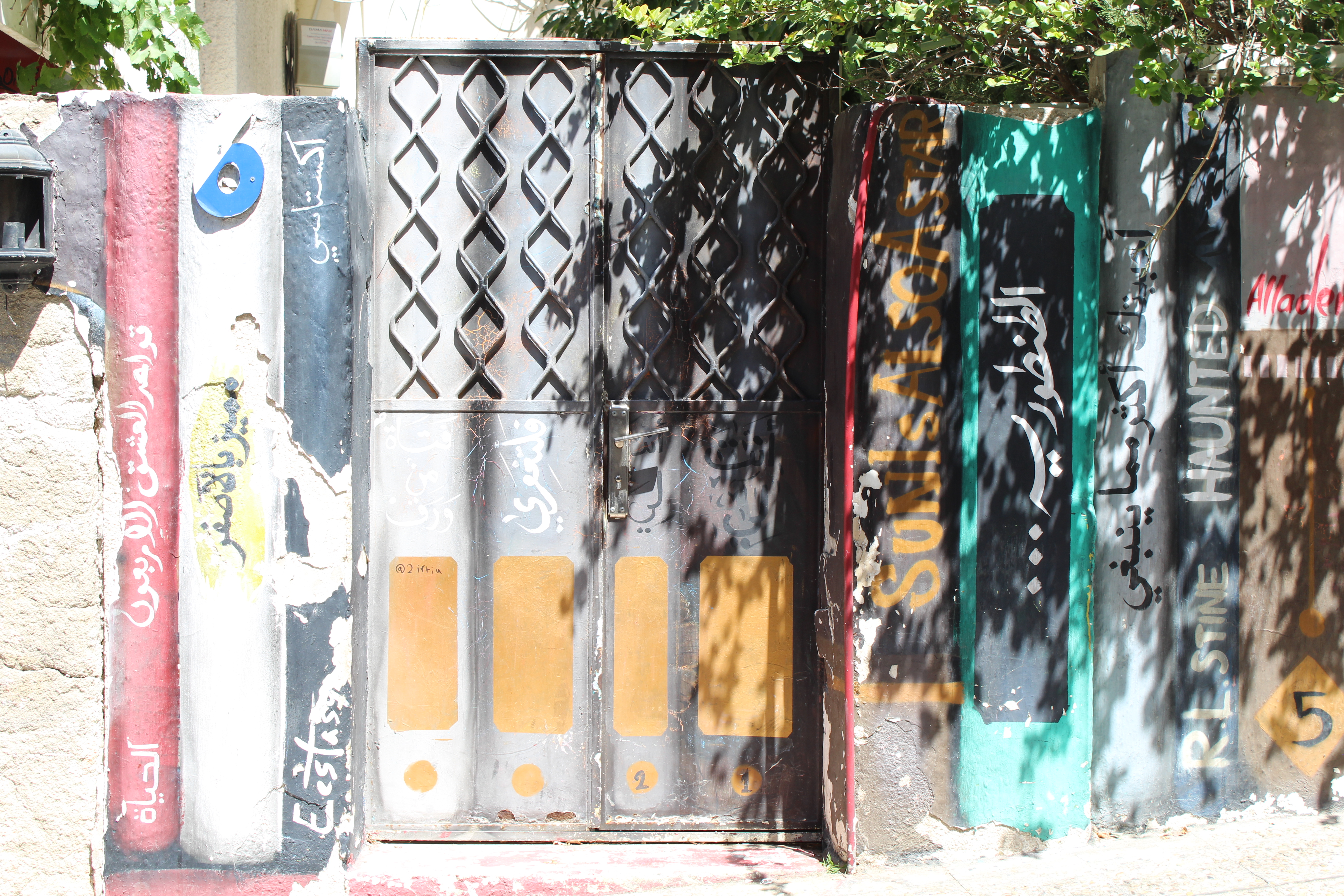 Colourful painted door and gate with Arabic calligraphy and graffiti on Rainbow Street Amman