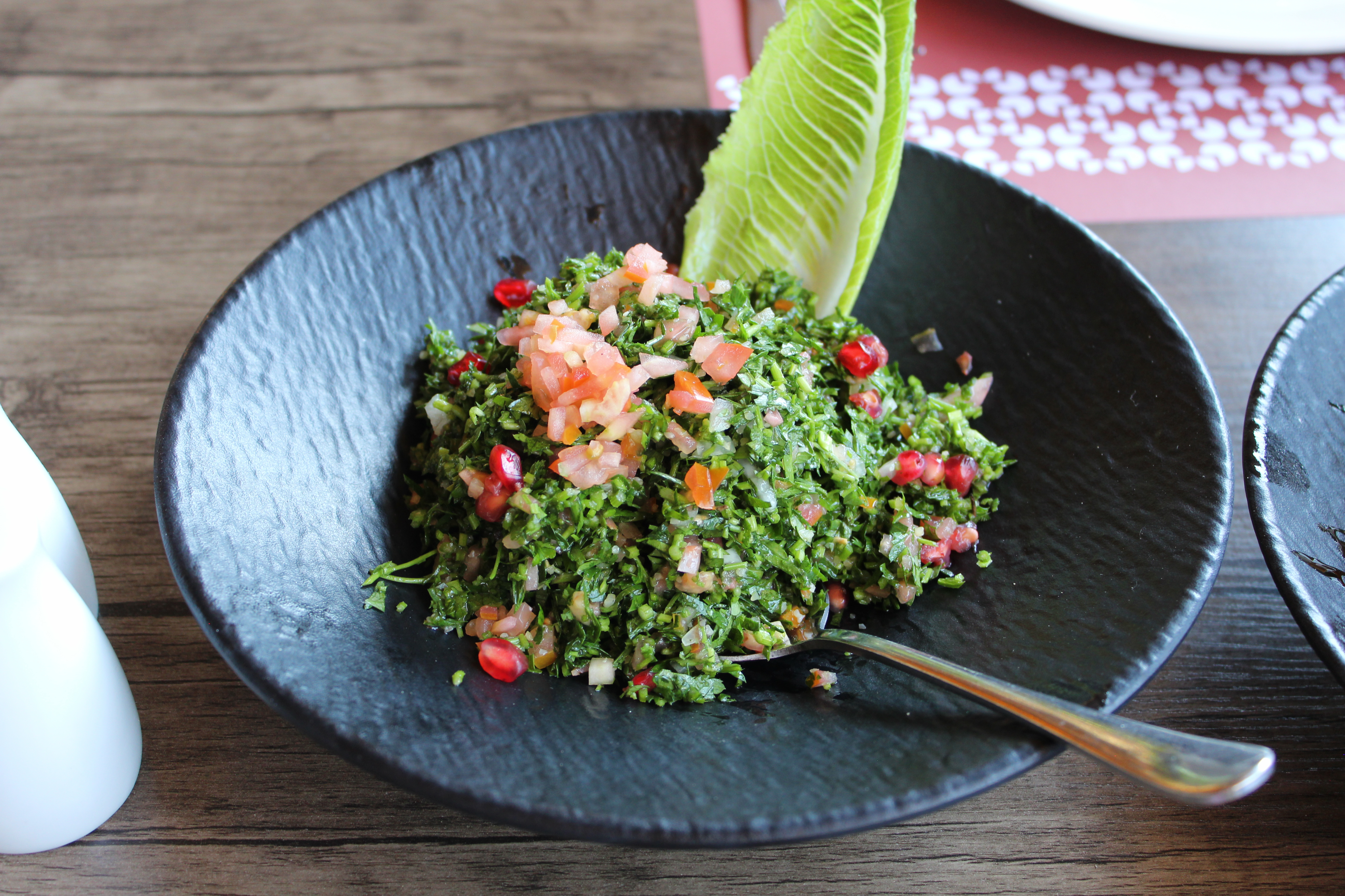 Tabbouleh salad with pomegranate on a black plate — a typical dish at a Jordanian breakfast spread