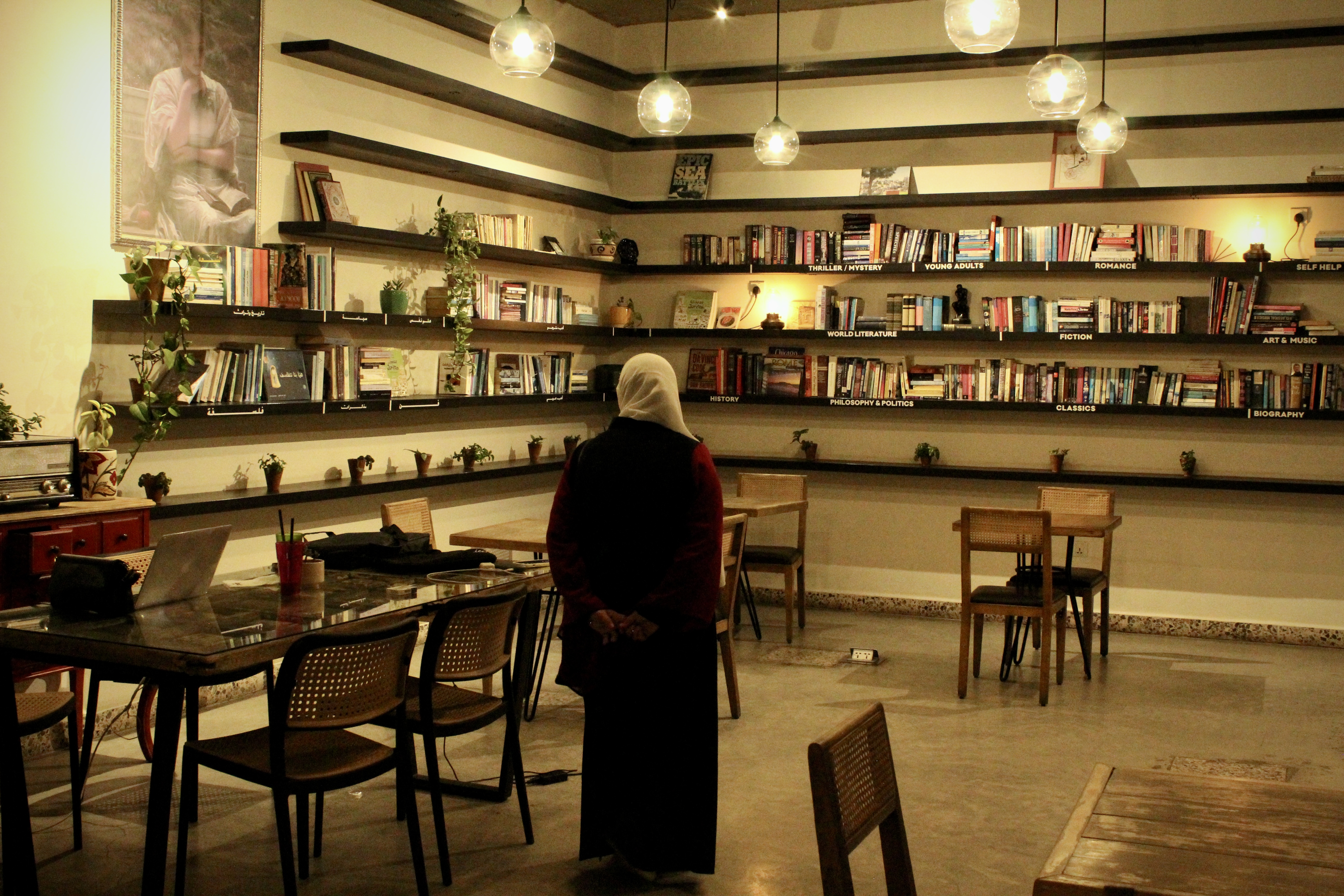 Warm café interior in Weibdeh Amman with bookshelves and pendant lights
